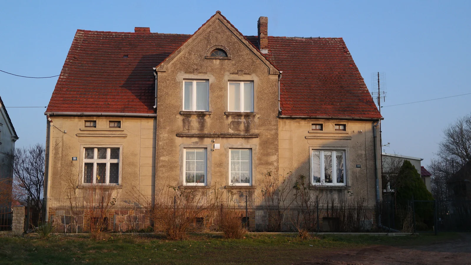 Älteres europäisches Wohnhaus mit hellem Mauerwerk und Ziegeldach.